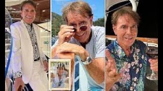 Sir Cliff Richard looks dapper in white suit as he poses on a boat and enjoys a drink in images [upl. by Ateekan]