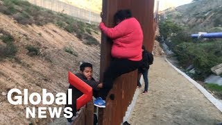 Migrant families continue to spill over Tijuana border fence head to US [upl. by Ikey]