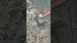 A worker on the bucket of a crawler excavator pulls something out of a rock with the bucket [upl. by Owena]